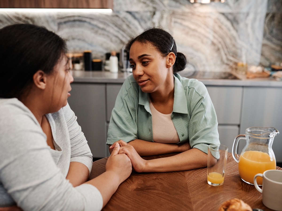 Two people in a warm, personal conversation at the kitchen table