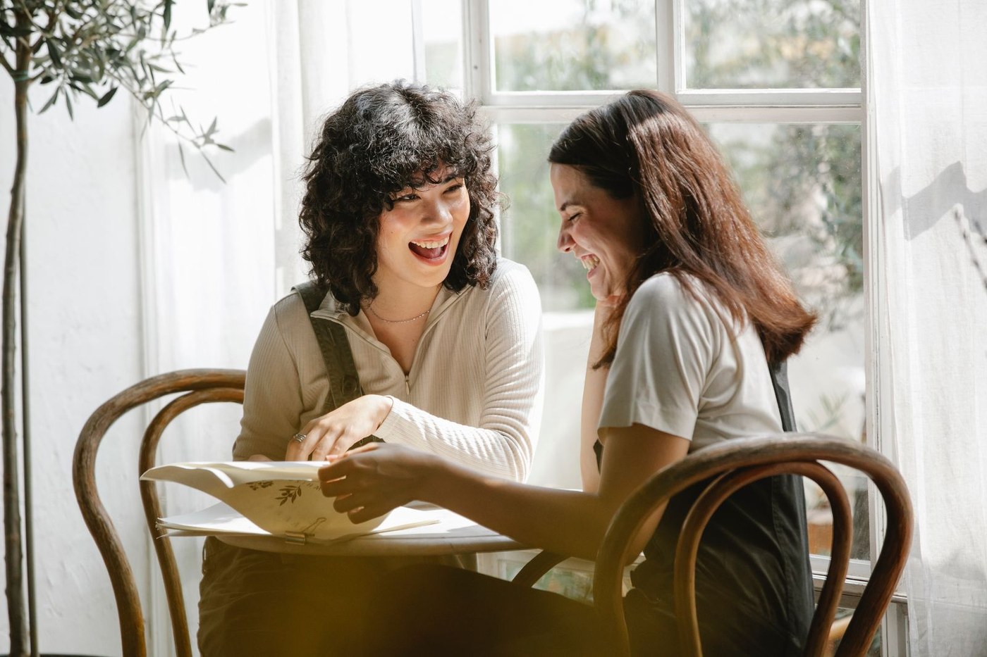 Two colleagues laughing together over paperwork, warm and genuine