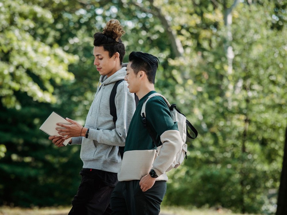 Two young people chatting as they walk together through a park
