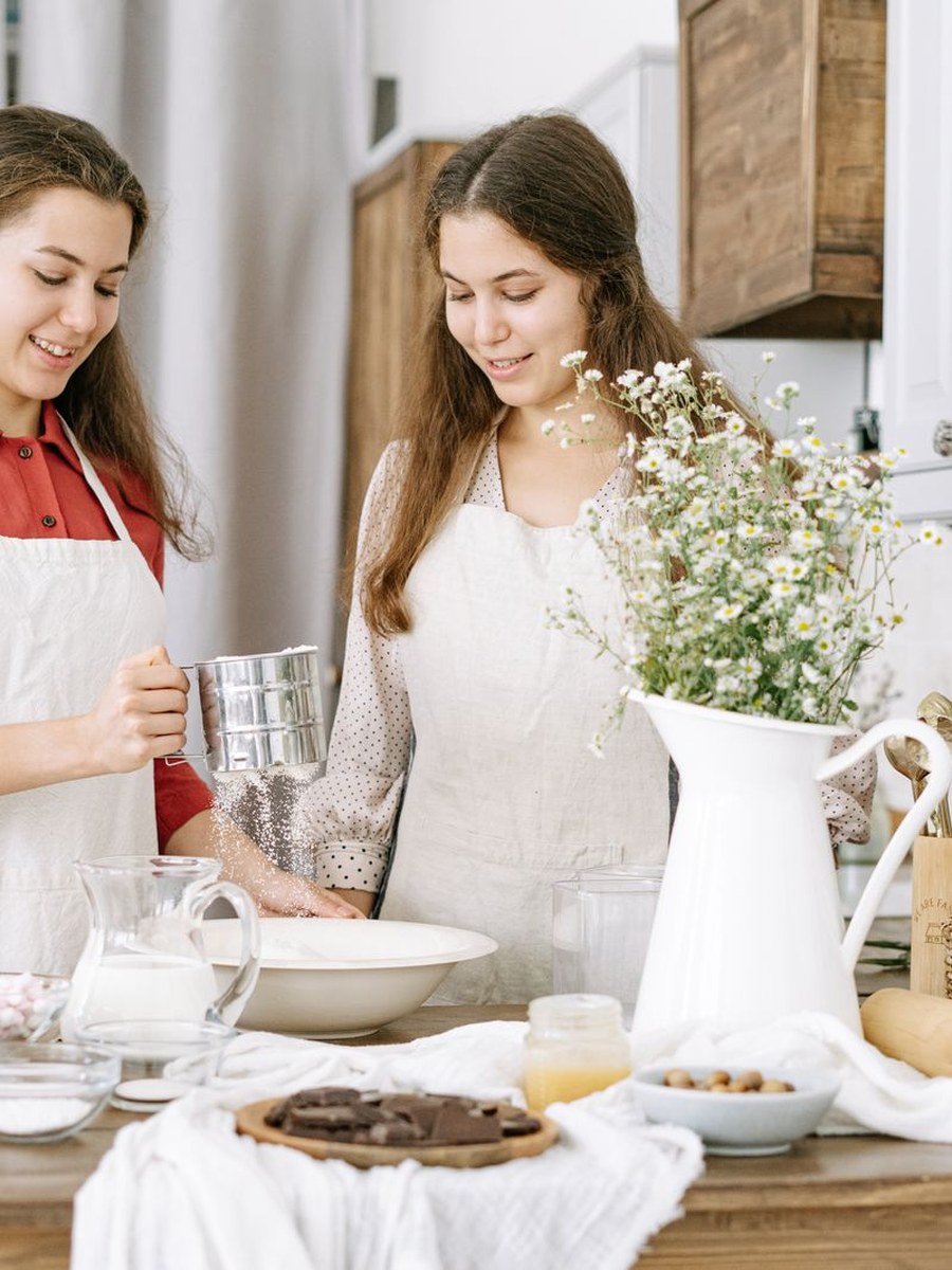 Two young people baking together, smiling over the mixing bowl