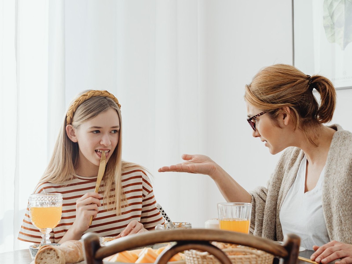 A teenager sharing a playful, laughing moment over breakfast at home