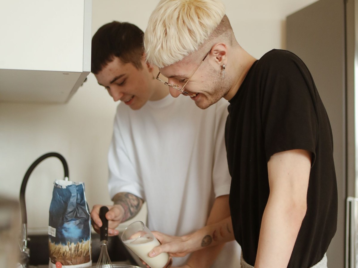 Two young adults baking together in the kitchen, relaxed and smiling