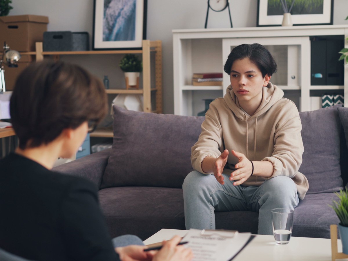 A support worker listening closely to a young person during a key-work conversation at home