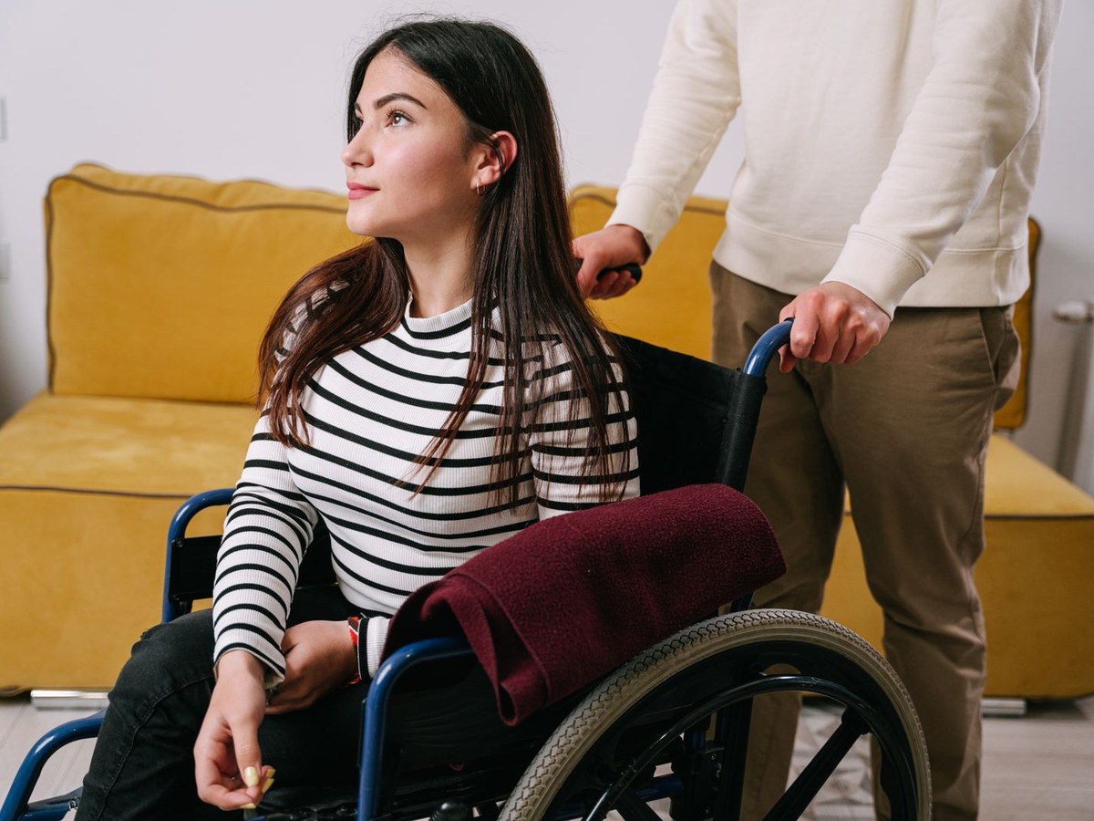 A young woman in a wheelchair sharing a warm moment with the person supporting her at home